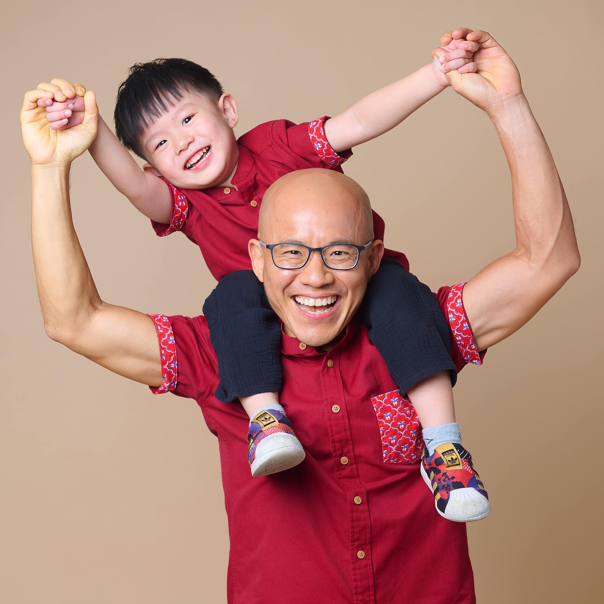 Daniel Tan smiling with his son on his shoulders